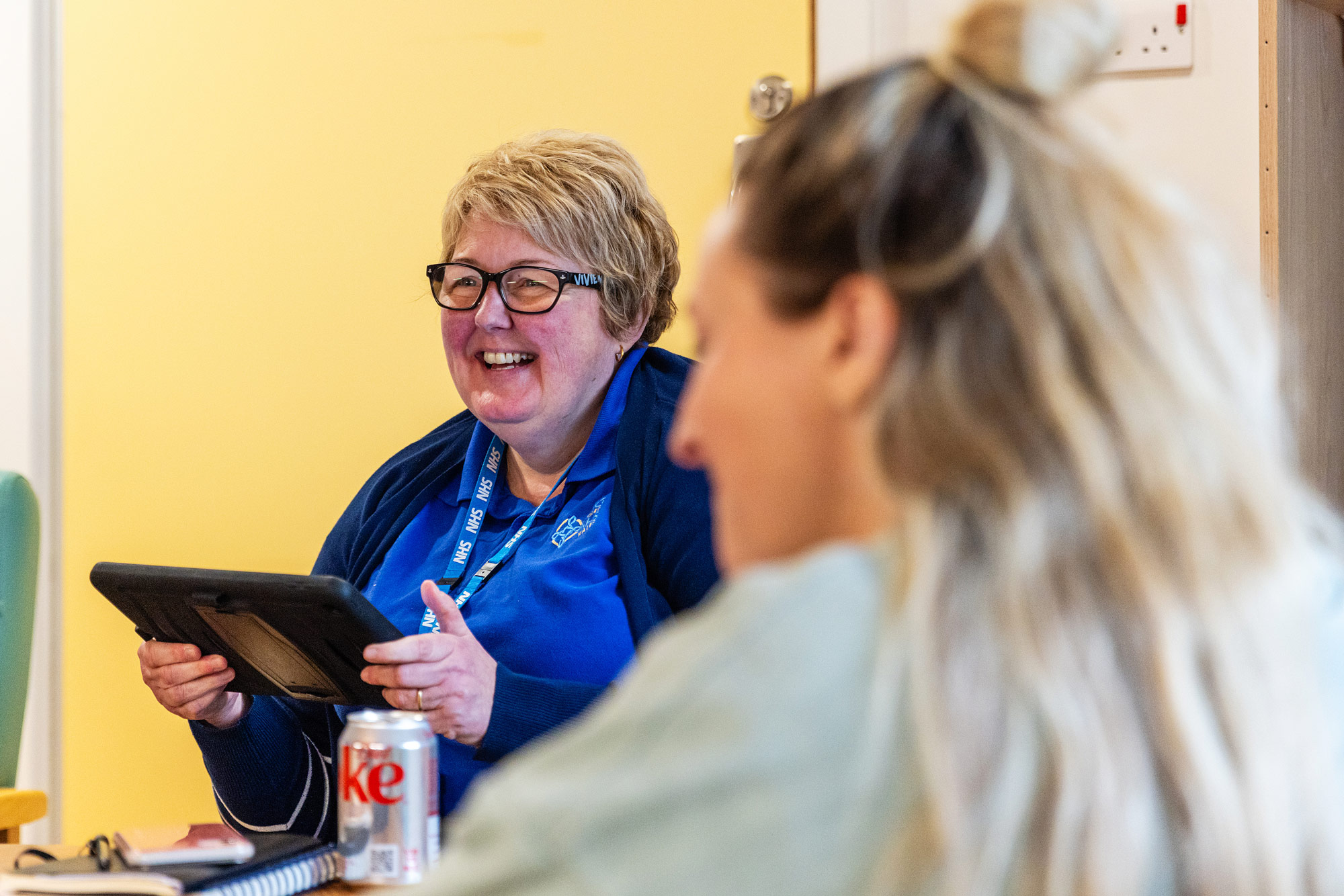 A staff member at CAVUHB smiles while using a tablet device