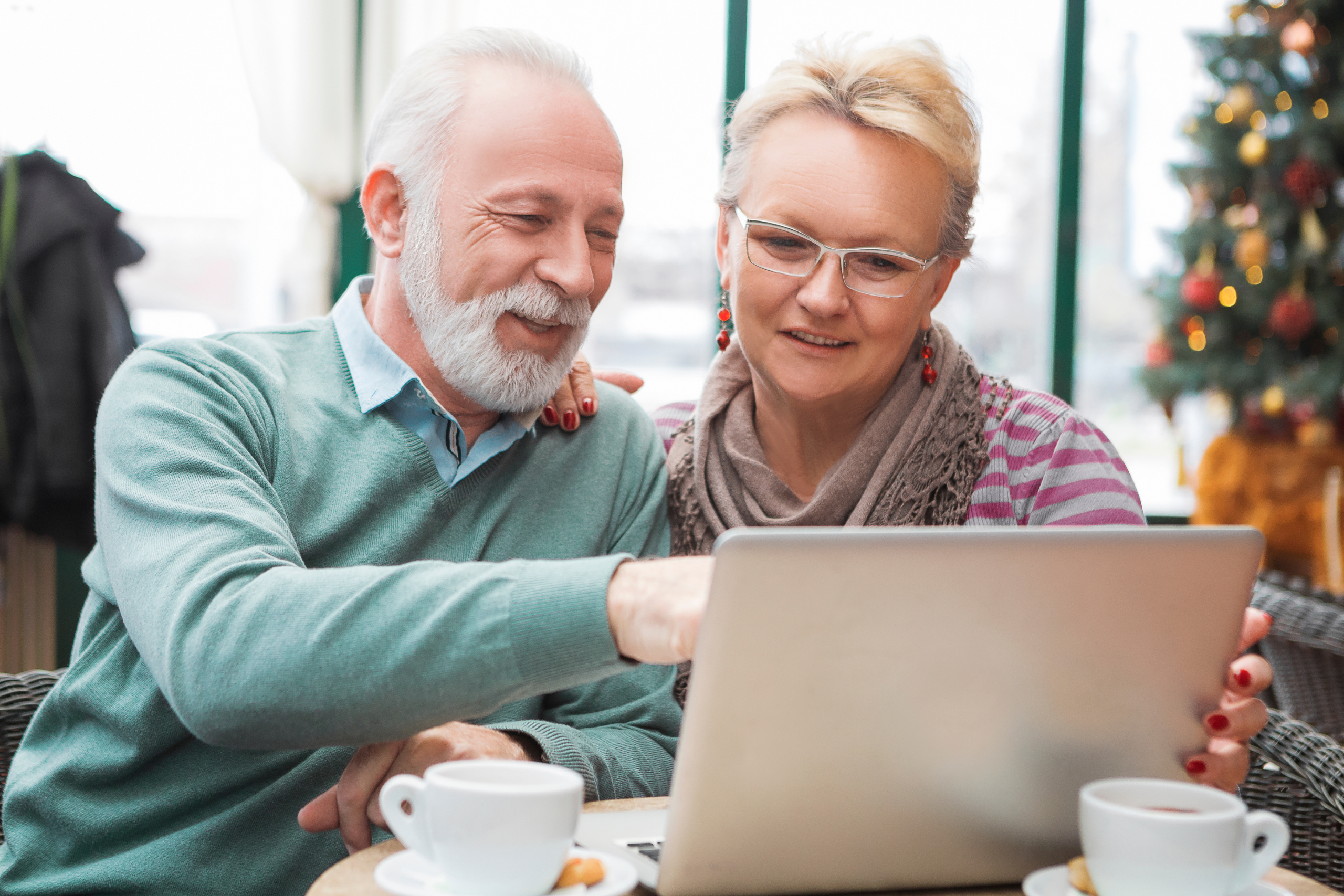 An older man and a woman use a laptop